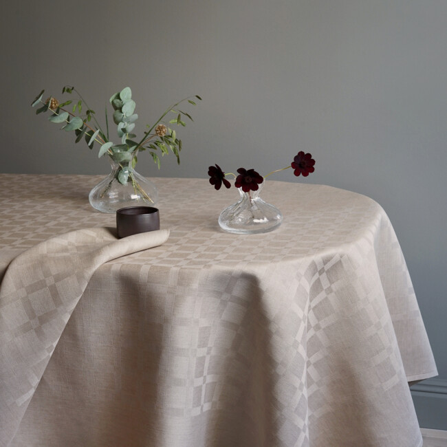 The linen cloth Dylta in the color sand together with the Dylta napkin in sand. Tablecloth with two knotted vases in transparent glass - Klassbol&#39;s linen vaveru