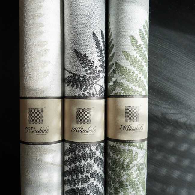 Fern table runners rolled up, in the colors black, black, moss green, by Klassbols Linnevaveri